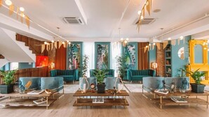 Un interior moderno con una escalera, sofás color aguamarina, mesas de centro de madera e iluminación decorativa.