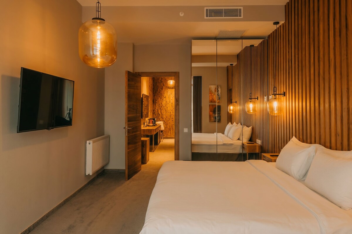 A modern hotel room with a large bed, a flat-screen TV, and a wooden accent wall.