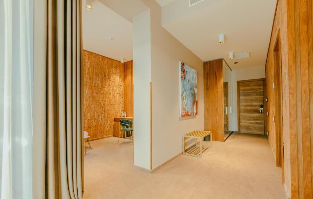 Un couloir aux murs en bois, avec un banc, une table et une porte.