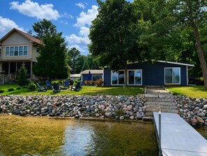 A residential property with a pond, a dock, a house, and a garage. - Updated Waterfront Cottage- Sandy Beach-Pier-Fishing-Bonfire-Sleeps up to 9 (Wild Rose)