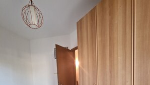 Quarto com cama, guarda-roupa e luminária suspensa.