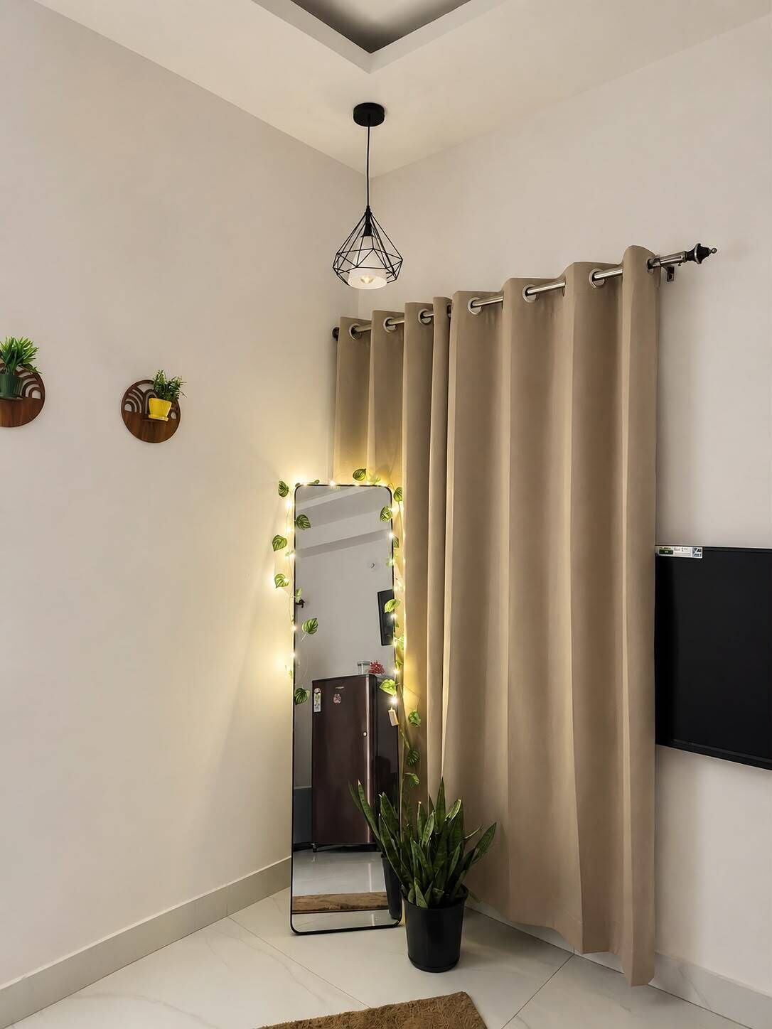Een moderne badkamer met een grote spiegel, beige gordijnen, een potplant en een plafondlamp.