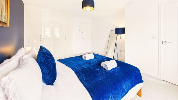 Una camera d'albergo con un letto, un armadio, uno specchio e una lampada da terra.