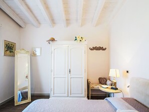 A bedroom with a bed, a wardrobe, a mirror, a small table with a lamp, and a chair. - La Casa di Menny by Interhome (Moneglia)