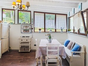 A kitchen with a dining area, wooden flooring, and a view of greenery outside. - La Casa di Menny by Interhome (Moneglia)