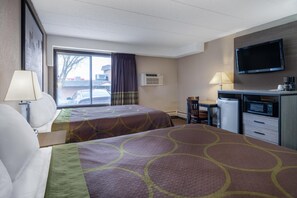 Une chambre d’hôtel avec deux lits, un bureau, une télévision et un réfrigérateur.