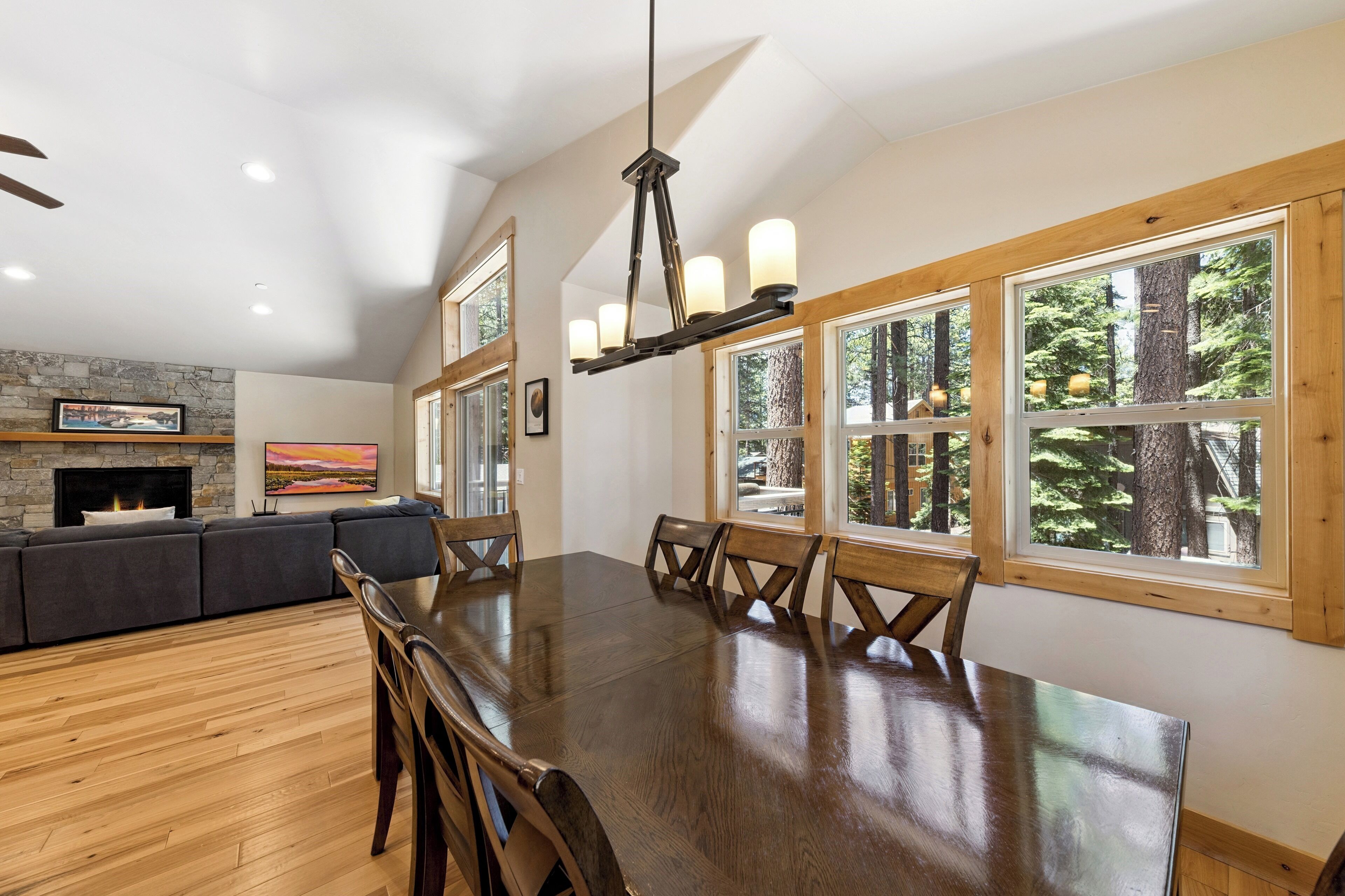 A dining area with a large wooden table, multiple chairs, and a stone fireplace.