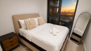 Una camera da letto moderna con un letto, un comodino e un'ampia finestra vista città.