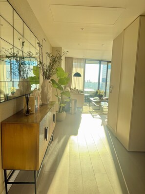 Een moderne hotelkamer met een houten console, potplanten, een groot raam en uitzicht op de skyline.