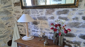 A wooden desk with a lamp, a vase with flowers, and a wall with a stone pattern. - Coastal Stone House in Lannilis for 5 (Lannilis)