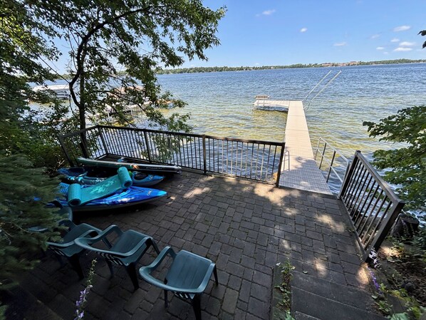 A dock with kayaks and chairs, a clear view of the lake, and a distant shoreline. - Darling Retreat- chain of lakes, new large deck, indoor sauna (Alexandria)