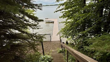 Un escalier en bois mène à une jetée surplombant l’eau, le tout étant entouré d’une végétation luxuriante.