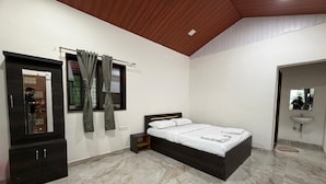 A bedroom with a bed, a wardrobe, a mirror, and a bathroom with a sink. - Ivystone Cottages (Bhilar)