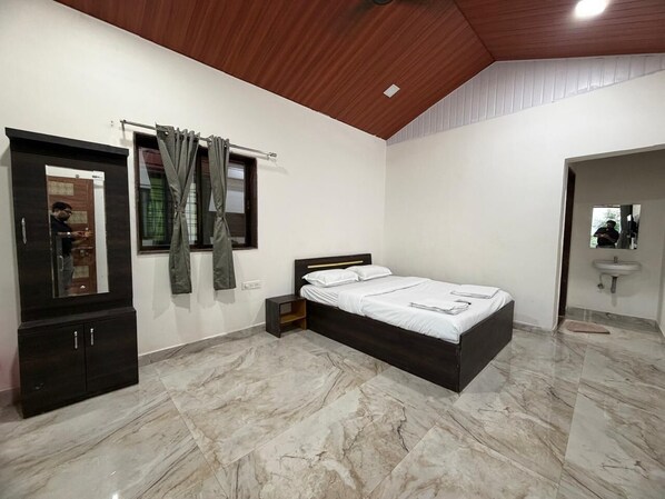 A bedroom with a bed, a wardrobe, a mirror, and a bathroom with a sink. - Ivystone Cottages (Bhilar)
