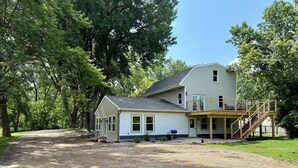 A two-story house with a covered porch and a staircase leading to a deck. - Lakeview Hideaway - Sleeps 14 - Family Retreat (Spirit Lake)