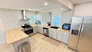 A modern kitchen with stainless steel appliances, light wood flooring, and a view of the outdoors. - Lakeview Hideaway - Sleeps 14 - Family Retreat (Spirit Lake)