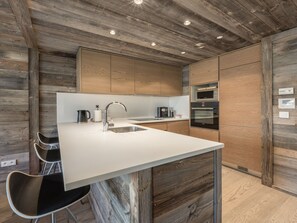 Une cuisine moderne avec des meubles en bois, un plan de travail blanc, un évier, une machine à café et un four encastré.
