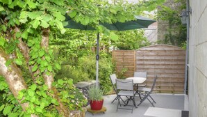 Un espace patio avec une table et des chaises, une plante en pot et une clôture en bois.