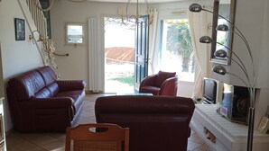 A living room with a sofa, a chair, a TV, and a staircase leading to an outdoor area. - House, pets allowed - 6 guests, 100m from the sea (Le Croisic)