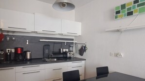 Een moderne keuken met witte kasten, een zwart aanrecht en een glazen tafel.