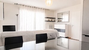 Een moderne, minimalistische slaapkamer met een bed, nachtkastjes, een spiegel en inbouwkasten.