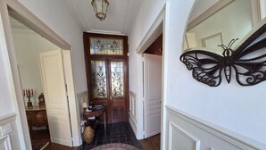 Un pasillo con una puerta de madera, un espejo con diseño de mariposa y un tapete estampado.