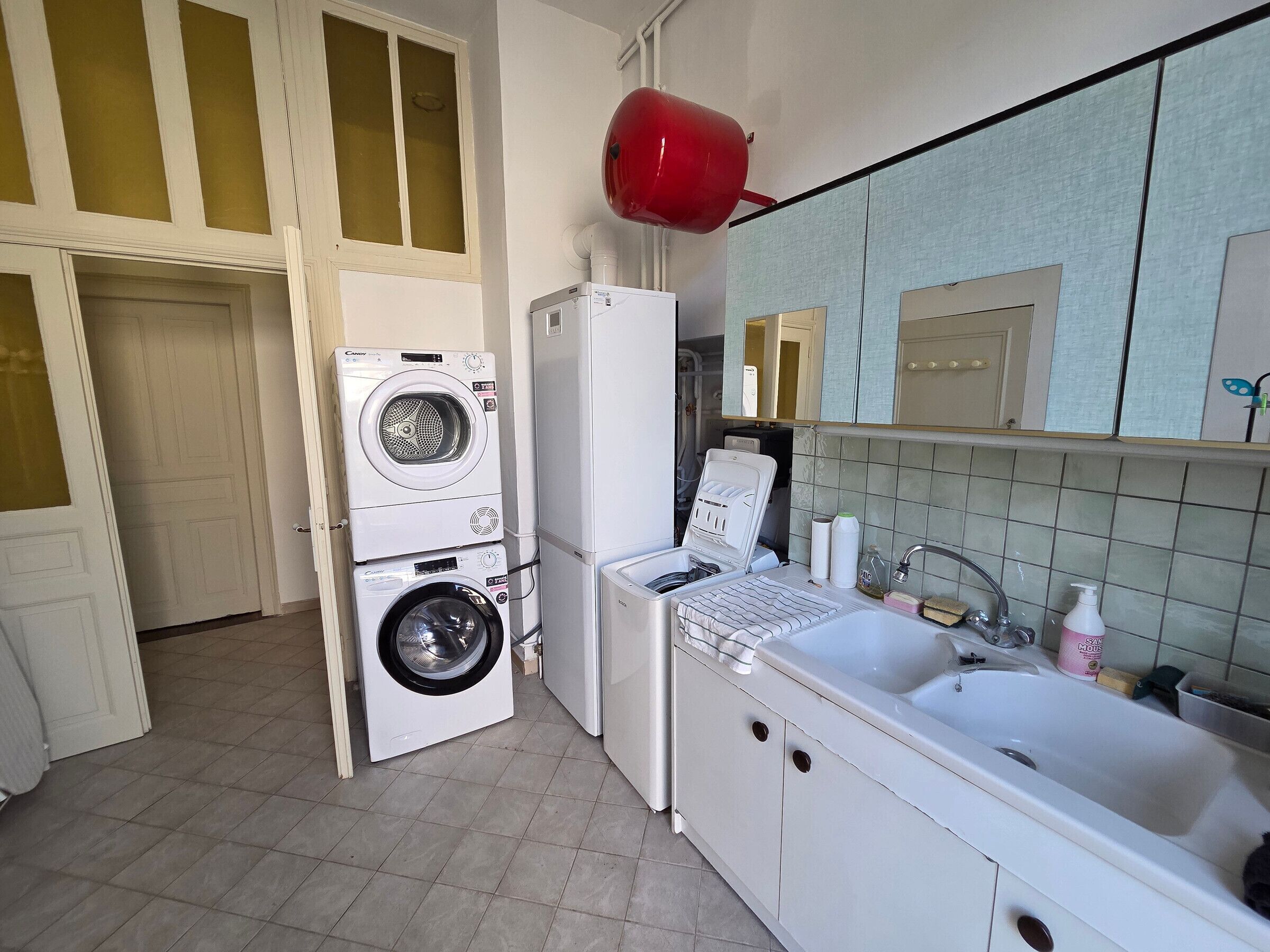 A compact kitchen with a washing machine, refrigerator, and sink.