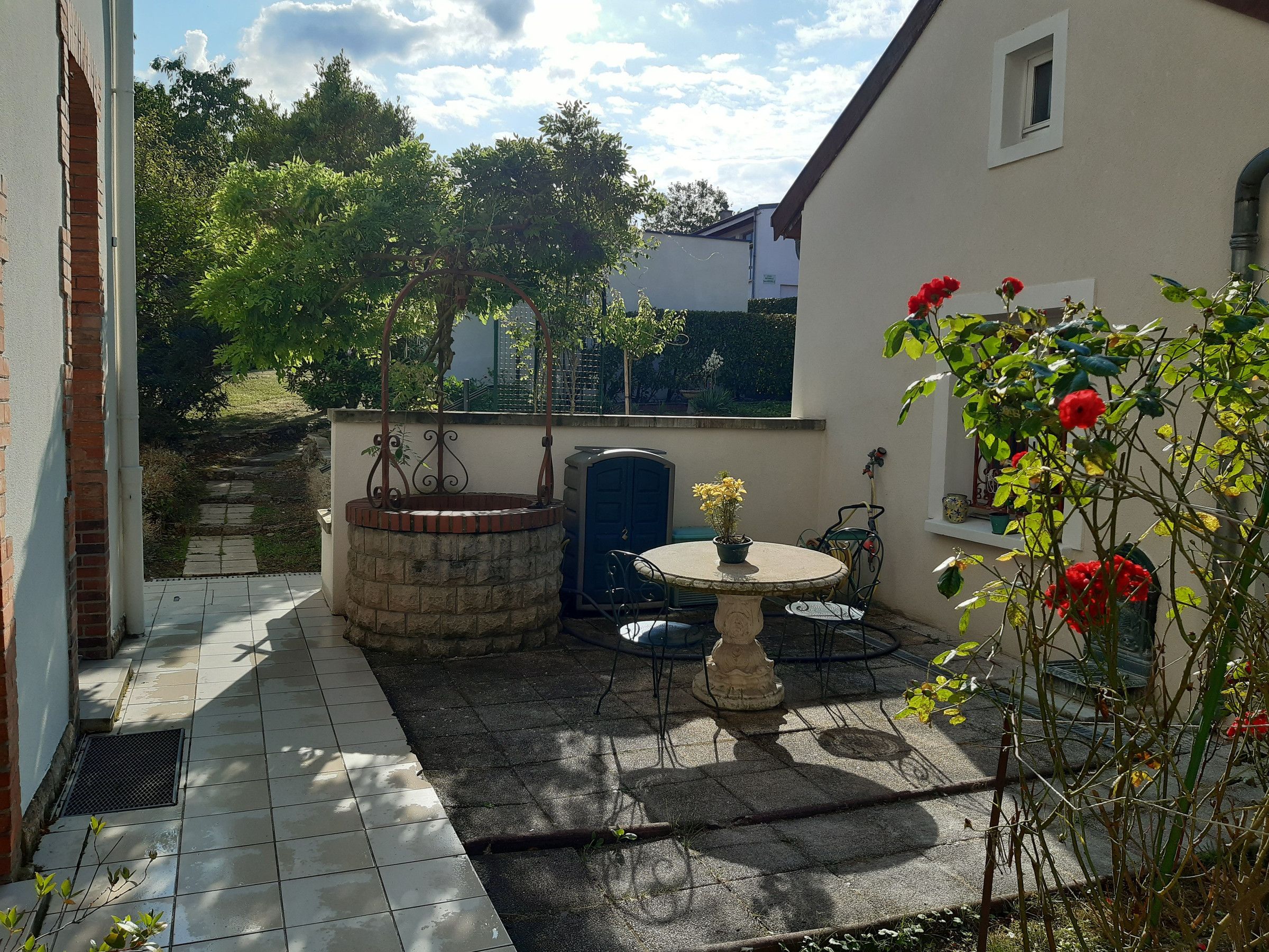 A patio area with a round table, a brick planter, and a blue door.