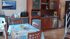 Una cucina compatta con mobili in legno, un forno a microonde, una moka e un'area pranzo con un tavolo apparecchiato per due.