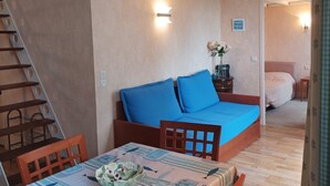 Una stanza con un letto a castello, un tavolo da pranzo con sedie, un tavolino con un vaso di fiori e un letto con materasso blu.