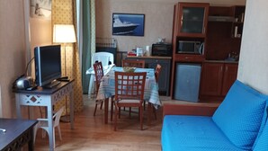 Un ambiente compatto con angolo ristoro, angolo cottura e un divano blu.