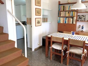 Ein Essbereich mit Holztisch und -stühlen, einem Bücherregal und einer Treppe.