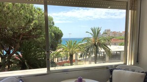 Una stanza con vista sul mare, un tavolo rotondo con una candela e due sedie con cuscini a quadri.