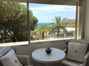 Ein Zimmer mit Meerblick, ein runder Tisch mit Kerze und zwei Stühle mit karierten Kissen.
