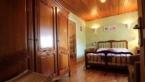 A wooden-paneled room with a bed, a bench, and a wardrobe.