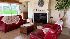 A living room with a fireplace, red leather sofas, a wooden coffee table, and a clock on the wall. - Large house, pets allowed - 14 guests (Pouzay)