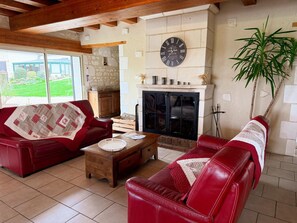 Ein Wohnzimmer mit Kamin, roten Ledersofas, einem Holztisch und einer Wanduhr.