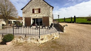 A stone building with a sloped roof, a covered patio with chairs, and a gravel driveway. - Large house, pets allowed - 14 guests (Pouzay)
