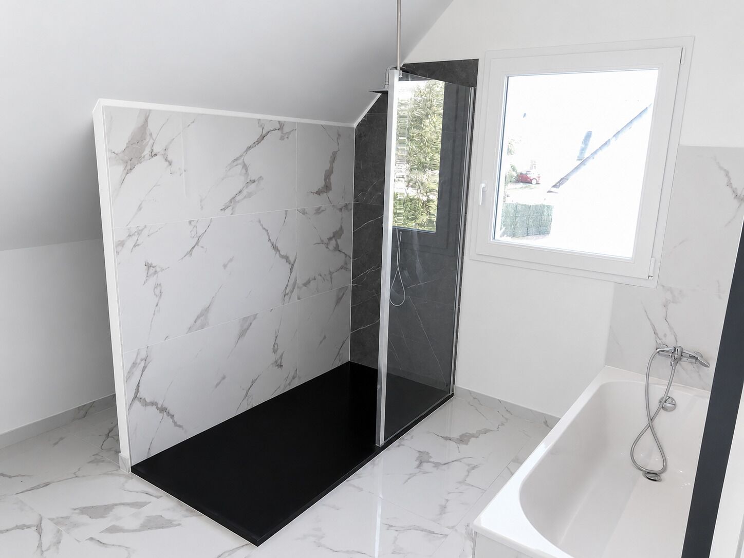 Un baño moderno con zona de ducha, bañera y ventana con vistas al exterior.