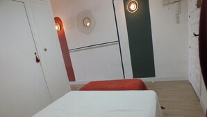 Ein Schlafzimmer mit einem Bett, einem Kleiderschrank, einer Tür und einer Wandleuchte.