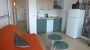 Ein kleines Zimmer mit einem Bett, einer Küchenzeile und zwei Barhocker.