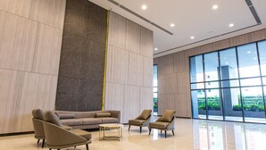 A modern lobby with a large sofa, two armchairs, a coffee table, and a large window with a view of greenery. - Equine Residence - Seri Kembangan (Seri Kembangan)