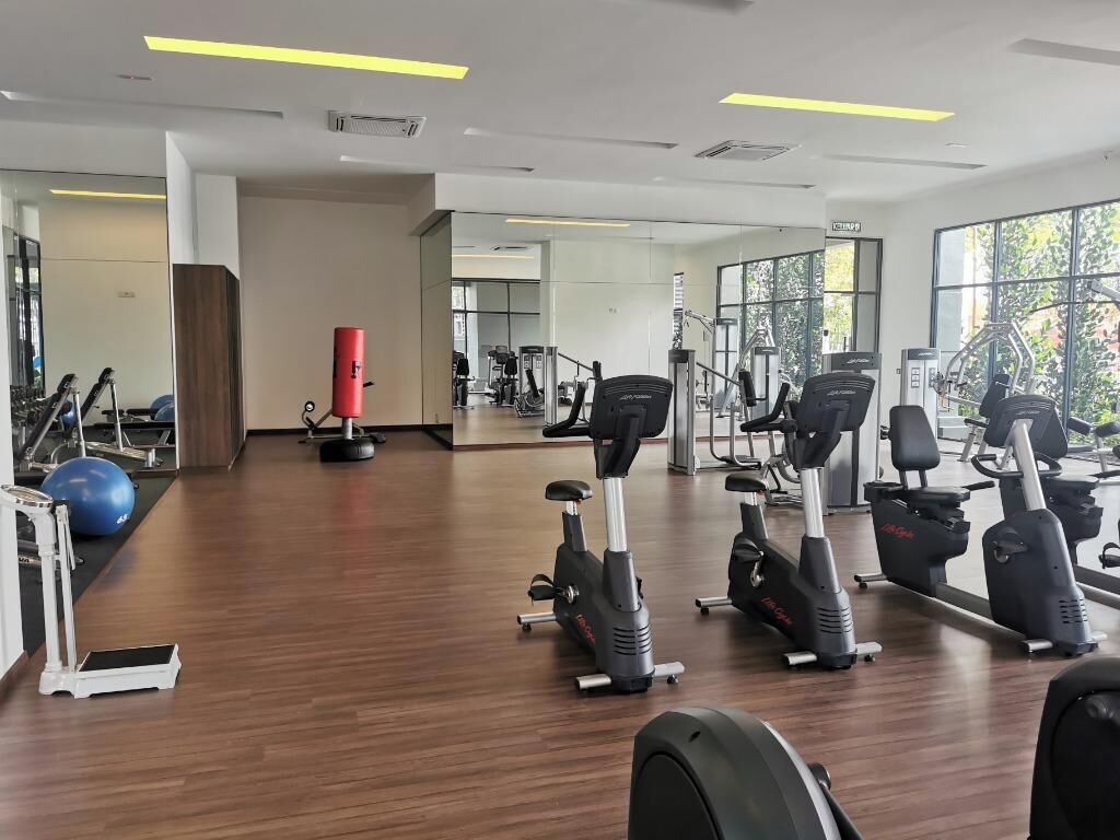 A gym with exercise equipment, a red punching bag, and large windows.