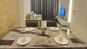 A dining room with a marble table set for four, a sofa, a TV, and a wall-mounted air conditioner. - Equine Residence - Seri Kembangan (Seri Kembangan)
