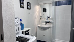 A compact bathroom with a washing machine, a sink, and a shower. - Quiet apartment with parking - 4 guests (Cauterets)