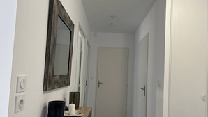 A hallway with a wooden console table, a mirror, a candle, and a door at the end. - Modern apartment with parking - 4 guests (Le Lavandou)