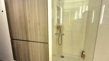 Une salle de bain avec une douche à parois de verre, un meuble en bois et un sol carrelé.