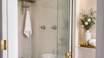 A modern bathroom with a glass-enclosed shower, a white sink, and a potted plant.