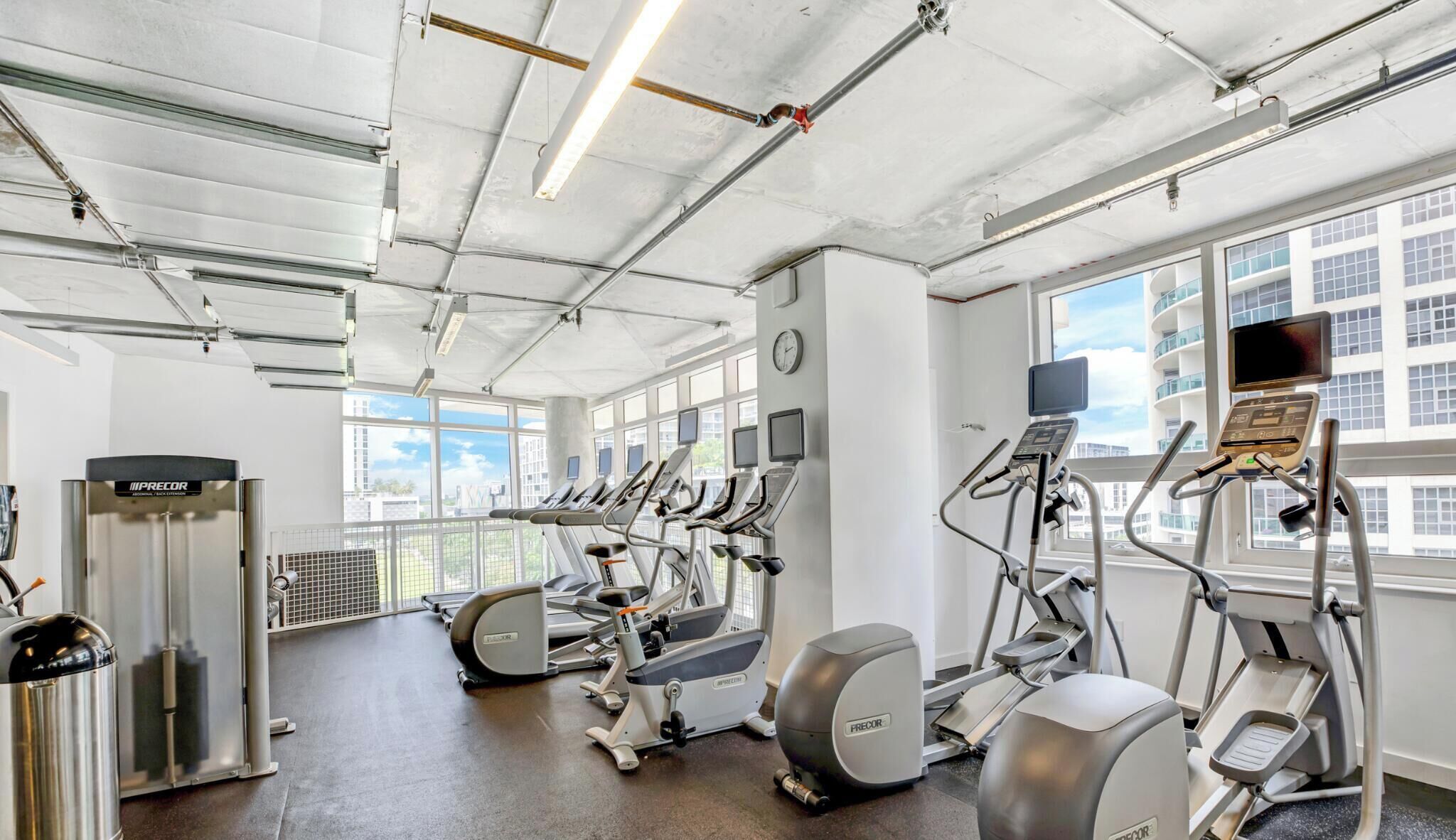 A gym with treadmills, elliptical machines, and a Precor stationary bike.