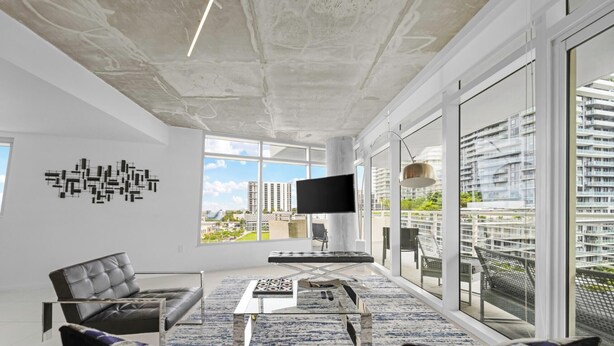 Una sala de estar moderna con sofá, mesa de centro y televisor de pantalla plana montado en la pared.